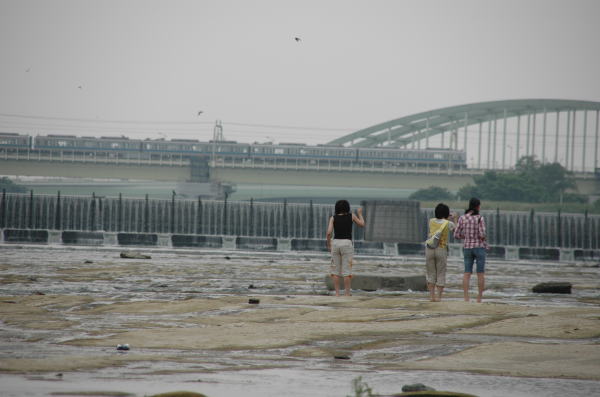 梅雨の間にも気温は高く、水が気持ちよい季節です。多摩川に足までつかり遊びながら川の写真を撮る女の子達と、川を渡る列車を対比してみました。