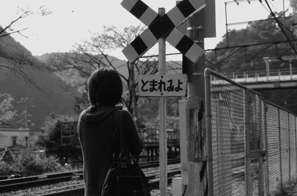 駅の近くの踏切で列車を待っていると若い2人連れの女性がやってきました。そもそもこんな小さな踏切に女性がやってくることが奇跡。風景の写真を撮りに来られたようです。踏切の標識の写真を撮ろうとしているところをお願いして、私が撮らせていただきました。