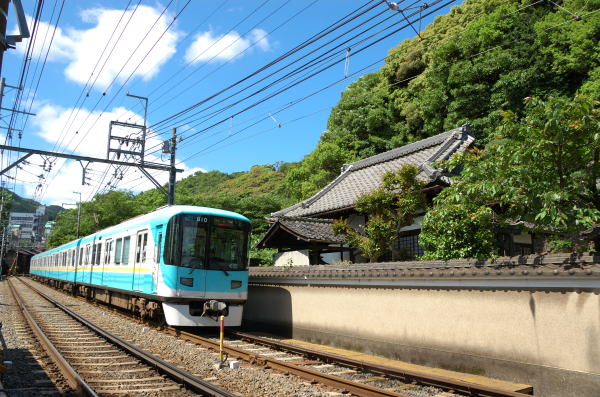 お寺の塀のすぐ横を列車が通過します。青空がまぶしい日でした。