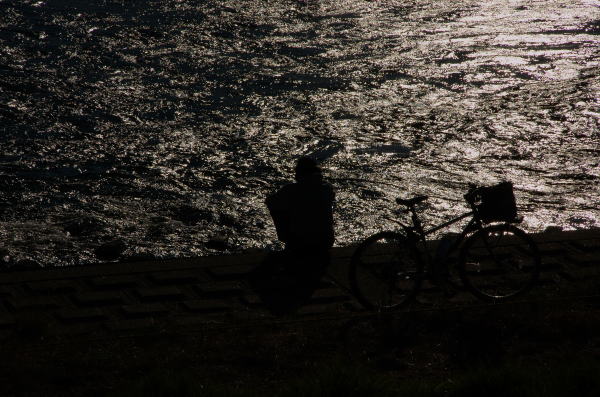 秋の昼下がり。川辺に自転車を留め座って川を眺める人がひとり。何を思っているのでしょうか。シルエット気味にして撮ってみました。